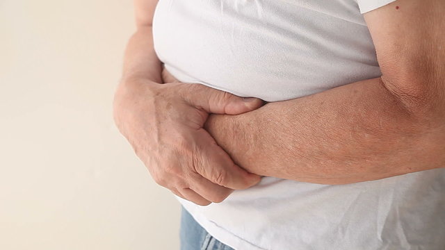 A man holds his stomach area while suffering from pain.