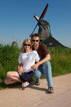 Couple of tourists on the background of a windmill. Concept: Tourism in Netherlands