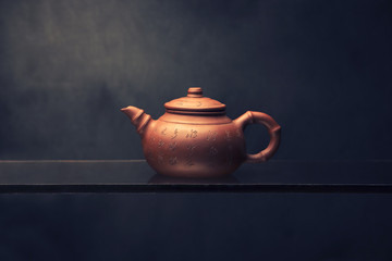 Chinese teapot with hieroglyphs on the glass on a dark background