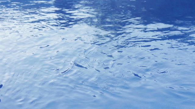 Closeup of water rippling on the surface of a blue swimming pool outdoor