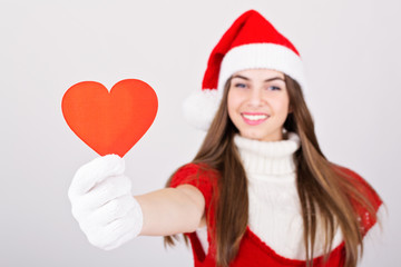 Happy teenage Santa Claus girl holding heart shaped paper