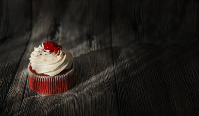 Red velvet cupcake decorated with vanilla cream on old grey wooden background