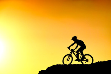 A cyclist riding down the hill with sunset silhouette