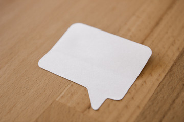 Selbstklebender Notizzettel in Sprechblasenform auf Holztisch