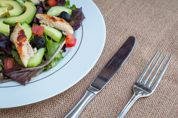 Chicken salad with avocado, mixed greens, cucumbers, tomatoes, and olives.