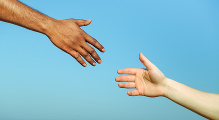 Black hand man helping white person - Different skin color hands united against racism and racial...