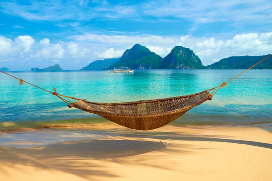 A hammock at the beach with the view of Bacuit Archipelago islands (El Nido, Philippines