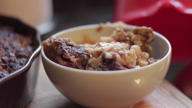 Closeup of a hot bowl of homemade apple crisp being topped with whipped cream