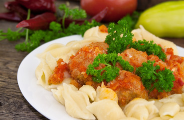 Pasta Conchiglie and meatballs with tomato sauce on rustic woode