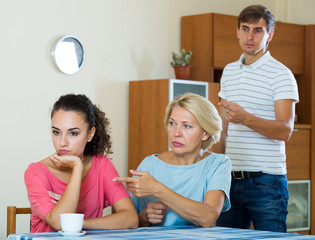 Elderly mother and young man blaming girl in something