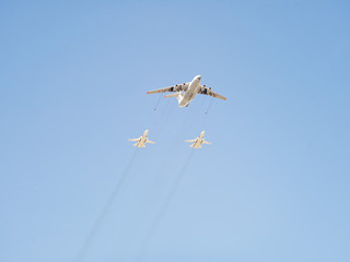 Ilyushin Il-78 (Midas) four-engined aerial tanker demonstrates refueling of 2 Sukhoi Su-24 (Fencer) supersonic all-weather attack aircrafts against blue sky background