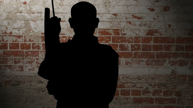 Black silhouetted man draws a Samurai Sword (Katana), and slashes through the air with sword and scabbard (siniwali style), then resheaths his blade in front of a brick background, with pan and zoom.