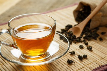 Cup of tea and leaves tea on wooden placemat