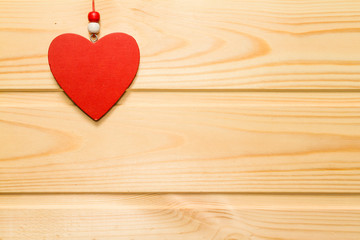 Wooden red heart suspended on a natural wood background.Valentin