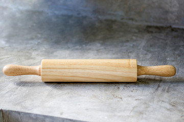 Wooden rolling pin, on cement floor background