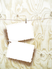 Two hanged postcards with pins on light brown wooden boards background