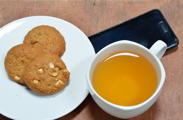 peanut cookie and cup of tea with black mobile phone
