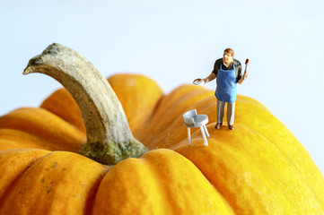 Miniature chef stand on yellow pumpkin