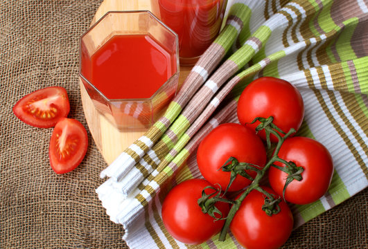 Tomato juice pour into glasses and ripe tomatoes..