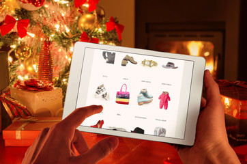 Christmas online shopping with tablet device. Christmas tree, gifts, lights and decorations.