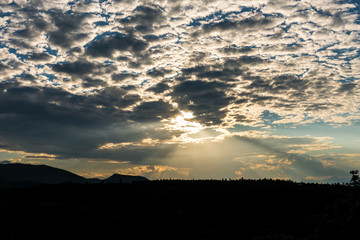 Crepuscular sun rays during sunset over the hill
