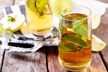 Glasses of apple juice with fruits and fresh mint on table close up