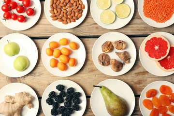 Different products on saucers on wooden table, top view