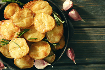 Delicious baked potato with rosemary in frying pan on table close up
