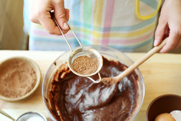 Woman preparing dough for chocolate pie on table close up