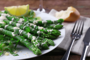 Served wooden table with asparagus dish and wine, close up