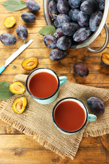 Plum Juice in mugs with fresh fruits