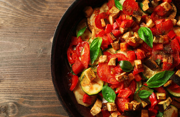 Tasty vegetarian ratatouille made of eggplants, squash, tomatoes and onions in black cast iron pan,...