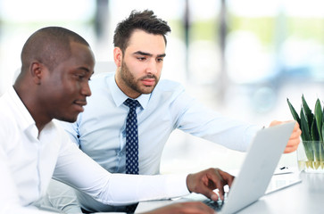 Fototapeta premium Image of two young businessmen interacting at meeting in office