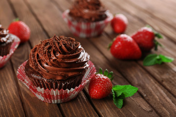 Chocolate cupcakes and strawberries on wooden background
