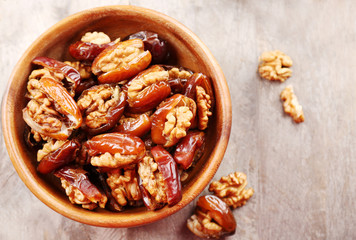 Walnut and date fruit in bowl on wooden table, close-up