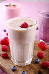 Milkshakes at cutting board with berries on light background, close-up