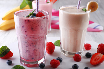 Milkshakes with berries on light wooden background, close-up