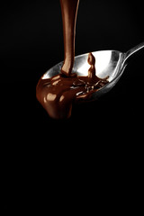 Chocolate poured on a spoon on dark background