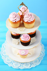 Tasty cupcakes on stand, on color background