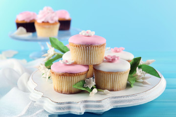 Tasty cupcakes on stand, on color wooden background