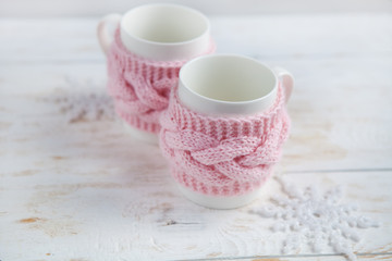 cup of hot tea in  knitted  cup holder on white wooden table