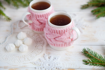 Fototapeta na wymiar cup of hot tea in knitted cup holder with sweets and christmas decorations
