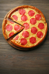 Hot tasty pizza with salami on wooden background