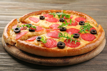 Hot tasty pizza with salami and olives on wooden background