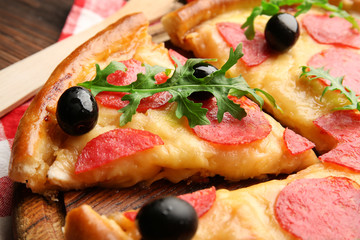 Delicious tasty pizza with salami and olives on wooden background, close up