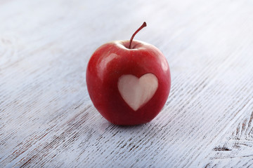 Apple with heart on wooden table