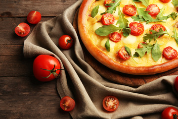 Pizza Margherita with arugula and vegetables on wooden table