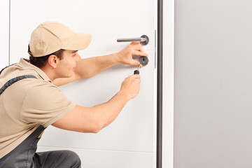 Young locksmith installing a lock on a door