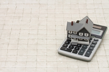 A gray house and calculator on stone background