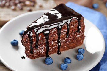Chocolate cake with chocolate cream and fresh blueberries on plate, on wooden background